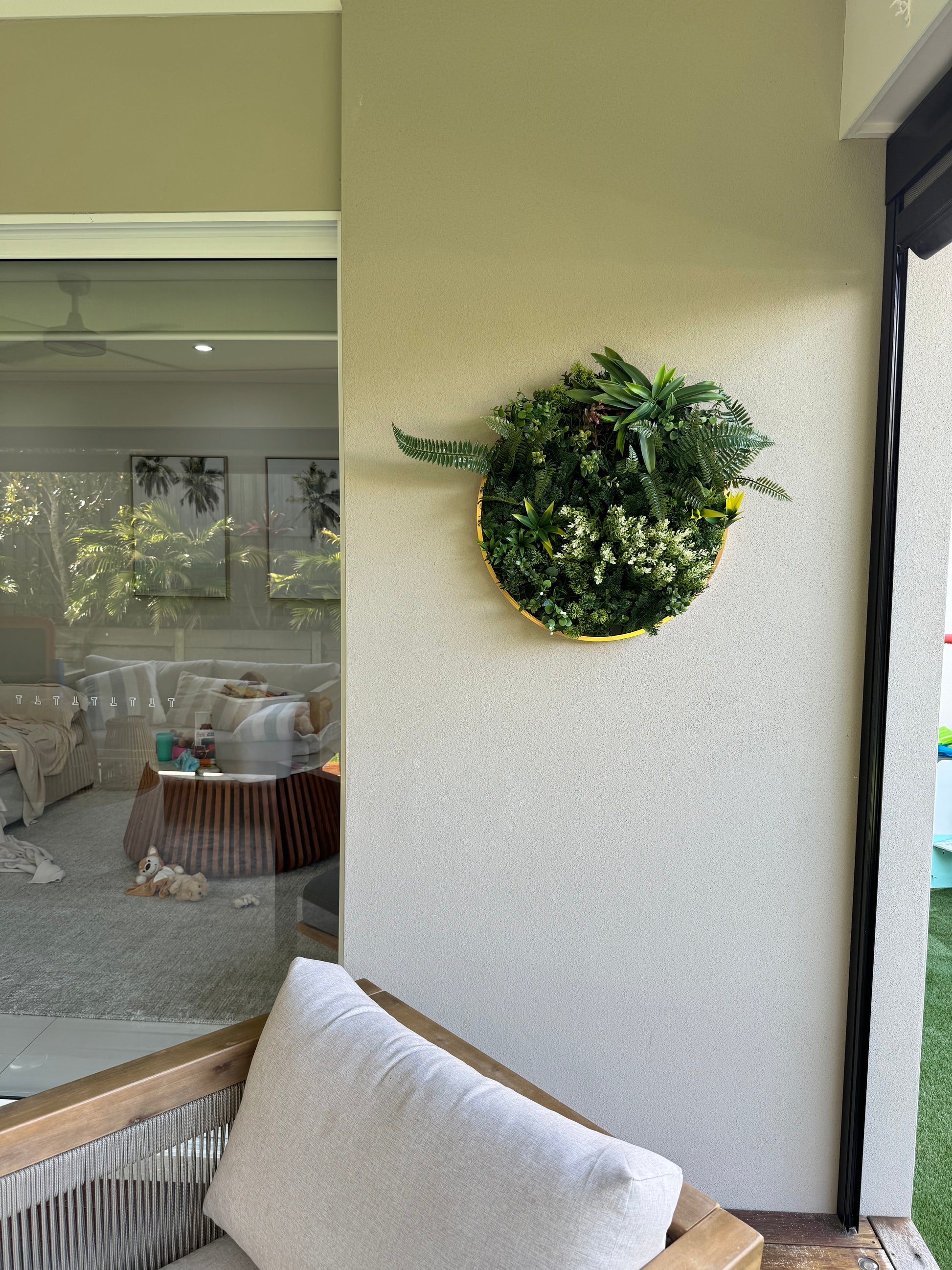 A artificial coastal green wall disc hung on a rendered wall.